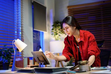 Kadın iç mimar gece geç saatlere kadar loş ışıklı stüdyosunda çalışıyor..