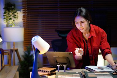 Kadın iç mimar gece geç saatlere kadar loş ışıklı stüdyosunda çalışıyor..