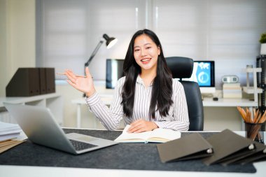 Ofiste dizüstü bilgisayarla çalışırken gülümseyen güzel bir kadın resmi.