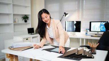 Belgeyi inceleyen kadın modern ofis masasında duruyor..