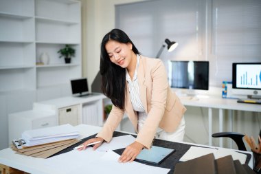 Belgeyi inceleyen kadın modern ofis masasında duruyor..