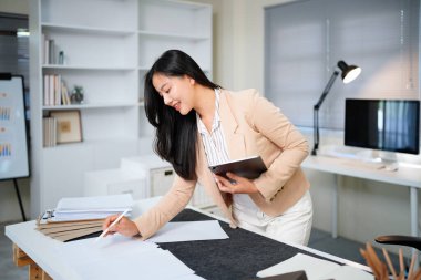 Belgeyi inceleyen kadın modern ofis masasında duruyor..