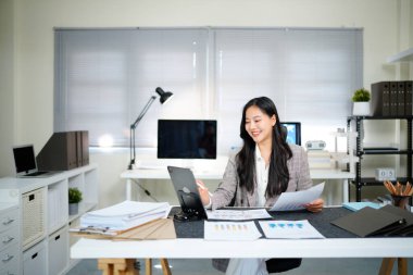 İş yerindeki başarılı ve neşeli kadın mali raporları ve sözleşmeleri kontrol ediyor. İş kadını ofis içinde evrak işleriyle uğraşıyor, tablet kullanıyor. Finansör vergi formlarını hazırlıyor ve dolduruyor.