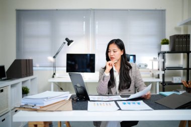 İş yerindeki başarılı ve neşeli kadın mali raporları ve sözleşmeleri kontrol ediyor. İş kadını ofis içinde evrak işleriyle uğraşıyor, tablet kullanıyor. Finansör vergi formlarını hazırlıyor ve dolduruyor.