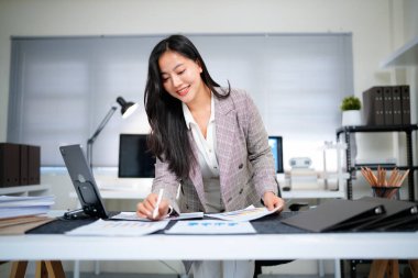 İş yerindeki başarılı ve neşeli kadın mali raporları ve sözleşmeleri kontrol ediyor. İş kadını ofis içinde evrak işleriyle uğraşıyor, tablet kullanıyor. Finansör vergi formlarını hazırlıyor ve dolduruyor.