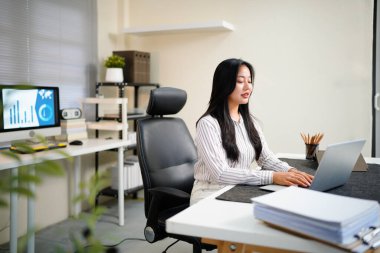 Modern ofisteki iş yerinde dizüstü bilgisayarla çalışan kendine güvenen bir iş kadını...