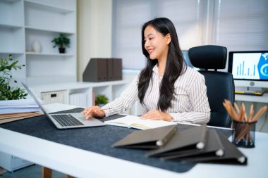 Modern ofisteki iş yerinde dizüstü bilgisayarla çalışan kendine güvenen bir iş kadını...