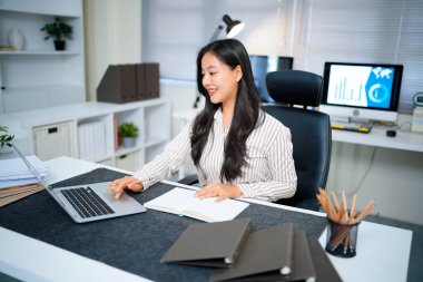 Modern ofisteki iş yerinde dizüstü bilgisayarla çalışan kendine güvenen bir iş kadını...