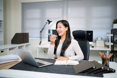 Voice note, chatting or talking of a woman on the phone at work in the office. Businesswoman talking on her speaker sending a voicemail or audio message to a colleague about work plan or schedule..