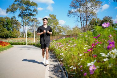 Mutlu ve gülümseyen Asyalı adam yaz aylarında emekli olduktan sonra parkta egzersiz yapıyor, koşuyor ya da rahatça yürüyor. Sağlık hizmetleri açık hava yaşam tarzı kavramı..