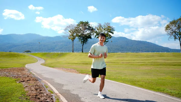 Mutlu ve gülümseyen Asyalı adam yaz aylarında emekli olduktan sonra parkta egzersiz yapıyor, koşuyor ya da rahatça yürüyor. Sağlık hizmetleri açık hava yaşam tarzı kavramı..