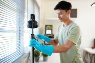 Ofisteki ıslak temizlik sırasında bilgisayar ekranını silmek için deterjan kullanan mavi eldivenli bir işçi..