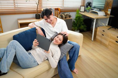 Gülüşmeler, tabletler ya da mutlu çiftler evde sevgi ve rahatlık için sosyal medyada rahatlamak için kanepede yatarlar. Mobil uygulama, bilgilendirme ve komik şakalar için kanepede gülümseyen insanlar..