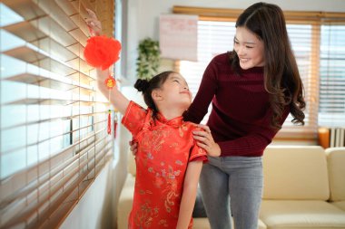 Asyalı anne ve kız, Çin Yeni Yıl kutlamaları için ev dekore ettiler. Evlerini canlı kırmızı fenerler ve Çin Yeni Yılı için diğer şenlikli dekorasyonlarla süslediler..