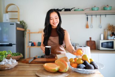 Önlüklü genç bayan kahvaltısını hazırla ve sabah kahvesinin keyfini çıkar, mutfağında..