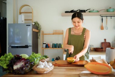 Modern mutfağın tahta tahtasında taze papaya dilimleyen bir kadın tropikal meyve hazırlama becerilerini titizlikle gösteriyor..