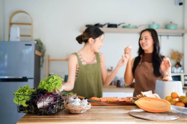 İki arkadaş, neşeli bir salata hazırlıyor. Güneşli bir mutfakta, kahkahalarımızı ve sağlıklı beslenme alışkanlıklarımızı paylaşıyoruz...