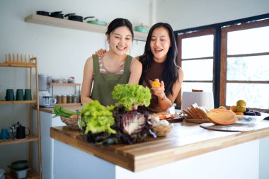 İki arkadaş, neşeli bir salata hazırlıyor. Güneşli bir mutfakta, kahkahalarımızı ve sağlıklı beslenme alışkanlıklarımızı paylaşıyoruz...