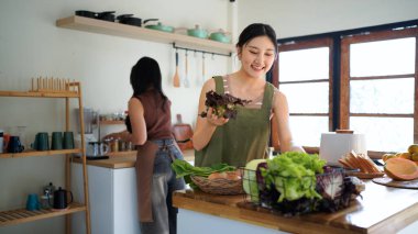 İki arkadaş, neşeli bir salata hazırlıyor. Güneşli bir mutfakta, kahkahalarımızı ve sağlıklı beslenme alışkanlıklarımızı paylaşıyoruz...