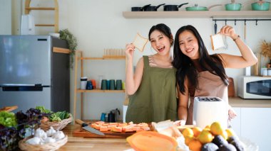 Kahvaltıda kızarmış ekmek yapmak için elektrikli tost makinesi kullanan iki genç kadın. Kızarmış ekmek yapmak için elektrikli tost makinesi kullanan iki kadın ve lezzetli bir kahvaltı..