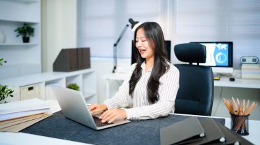 Modern ofisteki iş yerinde dizüstü bilgisayarla çalışan kendine güvenen bir iş kadını..