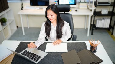 Modern ofisteki iş yerinde dizüstü bilgisayarla çalışan kendine güvenen bir iş kadını..