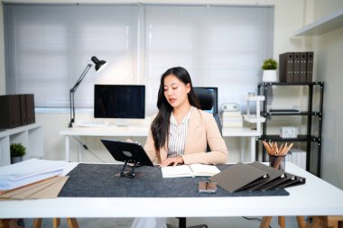 Genç bir kadın iş uygulaması için ped bilgisayar kullanıyor. Modern ofis işyerinde çalışmak için dijital tablet bilgisayar cihazını elinde tutan iş kadını CEO 'su..