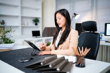 Genç bir kadın iş uygulaması için ped bilgisayar kullanıyor. Modern ofis işyerinde çalışmak için dijital tablet bilgisayar cihazını elinde tutan iş kadını CEO 'su..