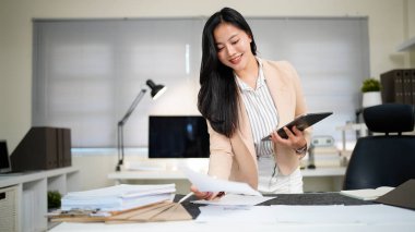 Belgeyi inceleyen kadın modern ofis masasında duruyor..