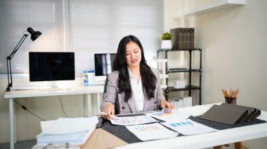 Bitmemiş belgeyi aramak ve kontrol etmek için tablet kâğıt dosyaları üzerinde çalışan iş kadını, yoğun çalışma masasındaki klasörlerdeki belgelerde başarıya ulaştı.