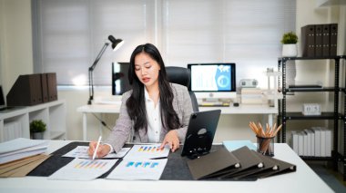 Bitmemiş belgeyi aramak ve kontrol etmek için tablet kâğıt dosyaları üzerinde çalışan iş kadını, yoğun çalışma masasındaki klasörlerdeki belgelerde başarıya ulaştı.