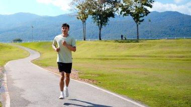 Mutlu ve gülümseyen Asyalı adam yaz aylarında emekli olduktan sonra parkta egzersiz yapıyor, koşuyor ya da rahatça yürüyor. Sağlık hizmetleri açık hava yaşam tarzı kavramı.