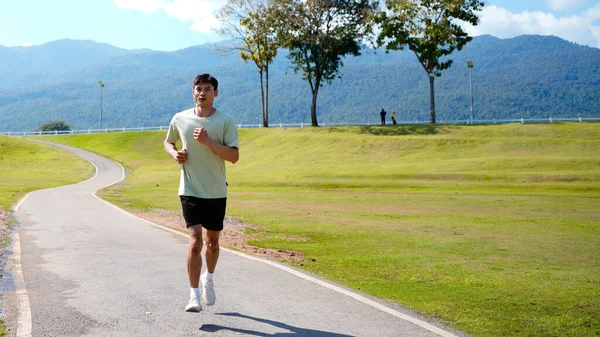Mutlu ve gülümseyen Asyalı adam yaz aylarında emekli olduktan sonra parkta egzersiz yapıyor, koşuyor ya da rahatça yürüyor. Sağlık hizmetleri açık hava yaşam tarzı kavramı.