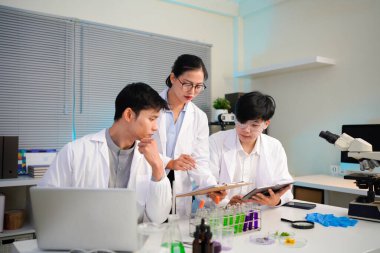 Veri tabloları ve laboratuvar sonuçları üzerinde işbirliği yapan bir bilim adamı ekibi modern bir laboratuvar ortamında çığır açan araştırmalar üzerinde çalışan kendini adamış bilim adamları..