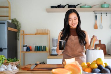 Önlüklü genç bayan kahvaltısını hazırla ve sabah kahvesinin keyfini çıkar, mutfağında..