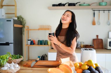 Önlüklü genç bayan kahvaltısını hazırla ve sabah kahvesinin keyfini çıkar, mutfağında..