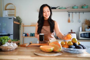 Önlüklü genç bayan kahvaltısını hazırla ve sabah kahvesinin keyfini çıkar, mutfağında..