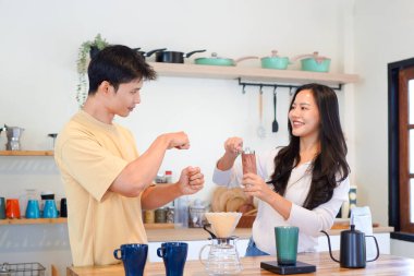 Birkaç Asyalı ya da bir çift kahve çekirdeğini öğütmeye, mutfakta kahve yapmaya ya da demlemeye. Bardak, kupa, şişe ve mutfak malzemelerini de masaya koyun. Sabah yaşam tarzı kavramı, aşk, mutluluk, aile, ilişki..