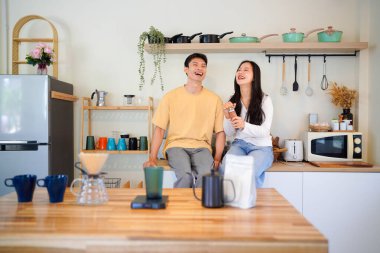 Birkaç Asyalı ya da bir çift kahve çekirdeğini öğütmeye, mutfakta kahve yapmaya ya da demlemeye. Bardak, kupa, şişe ve mutfak malzemelerini de masaya koyun. Sabah yaşam tarzı kavramı, aşk, mutluluk, aile, ilişki..