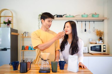 Birkaç Asyalı ya da bir çift kahve çekirdeği koklayacak, mutfakta kahve yapacak ya da demleyecek. Bardak, kupa, şişe ve mutfak malzemelerini de masaya koyun. Sabah yaşam tarzı kavramı, aşk, mutluluk, aile, ilişki..