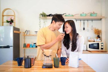 Birkaç Asyalı ya da bir çift kahve çekirdeği koklayacak, mutfakta kahve yapacak ya da demleyecek. Bardak, kupa, şişe ve mutfak malzemelerini de masaya koyun. Sabah yaşam tarzı kavramı, aşk, mutluluk, aile, ilişki..