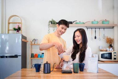 Mutlu bir çift kahvaltı için mutfakta birlikte damlatan bir kahve romantik bir sabah rutinini, kafeini ve aşkla kaynaşmayı gösteren sıcak bir ev hayatı anı..