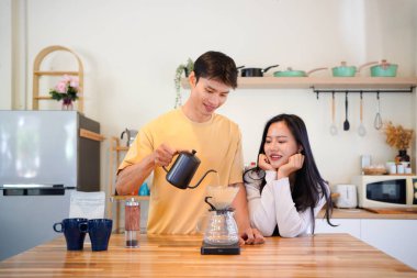 Mutlu bir çift kahvaltı için mutfakta birlikte damlatan bir kahve romantik bir sabah rutinini, kafeini ve aşkla kaynaşmayı gösteren sıcak bir ev hayatı anı..