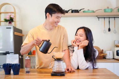 Mutlu bir çift kahvaltı için mutfakta birlikte damlatan bir kahve romantik bir sabah rutinini, kafeini ve aşkla kaynaşmayı gösteren sıcak bir ev hayatı anı..