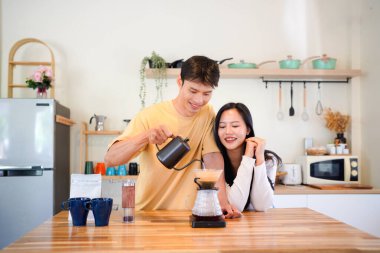 Mutlu bir çift kahvaltı için mutfakta birlikte damlatan bir kahve romantik bir sabah rutinini, kafeini ve aşkla kaynaşmayı gösteren sıcak bir ev hayatı anı..