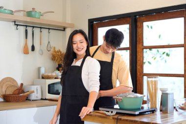 Erkek, kız arkadaşının önlüğünü arkadan bağlamasına yardım ederken evde kahvaltıya hazırlanıyor. Sabahları evde yemek ve kahvaltı..