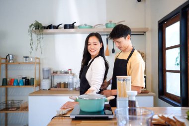Erkek, kız arkadaşının önlüğünü arkadan bağlamasına yardım ederken evde kahvaltıya hazırlanıyor. Sabahları evde yemek ve kahvaltı..