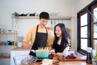 Yatay mutlu çift sıcacık bir ev mutfağında makarna pişiriyor sıcak ışık, tencere ve doğal renklerden yükselen buhar neşeli ve samimi bir atmosfer yaratıyor, yaşam tarzı için ideal..