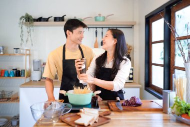 Yatay mutlu çift sıcacık bir ev mutfağında makarna pişiriyor sıcak ışık, tencere ve doğal renklerden yükselen buhar neşeli ve samimi bir atmosfer yaratıyor, yaşam tarzı için ideal..