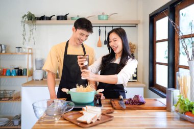 Yatay mutlu çift sıcacık bir ev mutfağında makarna pişiriyor sıcak ışık, tencere ve doğal renklerden yükselen buhar neşeli ve samimi bir atmosfer yaratıyor, yaşam tarzı için ideal..